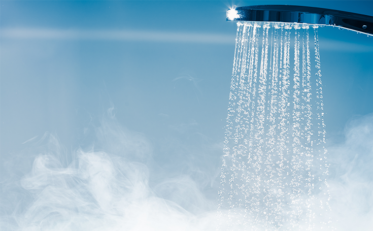 A showerhead releasing streams of water with visible steam rising, indicating hot water in use.